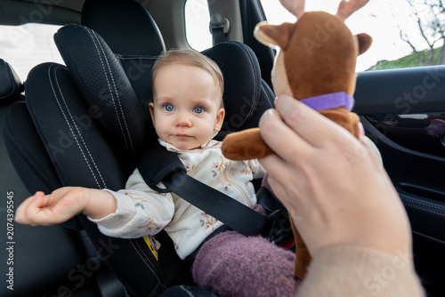 Photography Mother trying to entertain baby in car seat with a toy