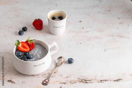Healthy breakfast chia pudding with berries and espresso on a light stone table
