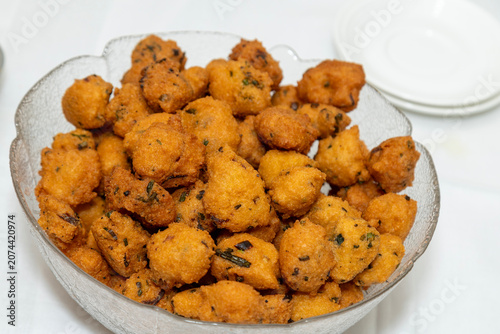 Crispy golden brown fritters filled with herbs served in a clear glass bowl