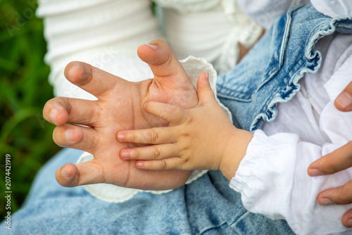 Mother and daughter holding hands outdoors close up