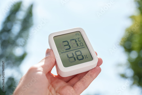 Hand holding digital thermometer during the summer 2026 heat wave in Germany