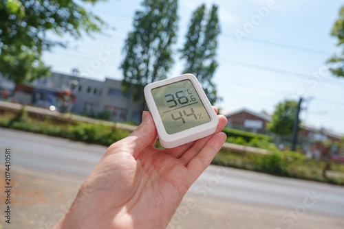 Hand holding digital thermometer during the summer 2026 heat wave in Germany
