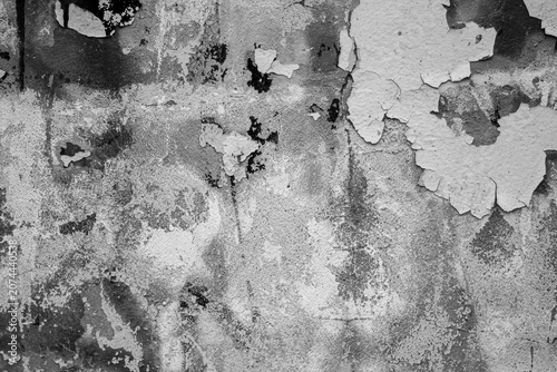 Texture of an old wall with peeling paint, cracks, and scuffs. The surface bears the marks of time: fading, stains, flaking paint layers, and an uneven texture. The black-and-white image highlights th