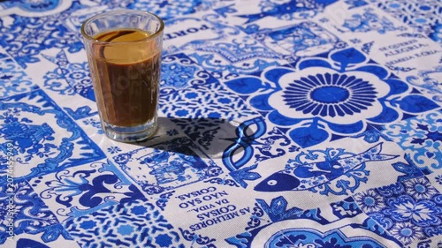 Hand placing one pastel de nata custard tart on white plate on azulejo