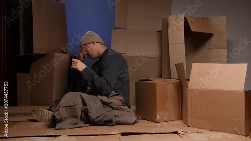 Foto Man suffering from poverty and addiction, covering his face in despair while hol