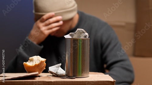Fotografía Homeless man, feeling desperate and hopeless, sitting on cardboard boxes with a