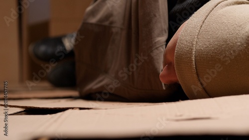 Fotografie Homeless person resting on makeshift bed of cardboard, representing social issue