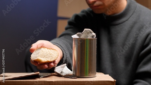 Φωτογραφία Person showing a piece of bread, experiencing poverty and hunger, with a metal c