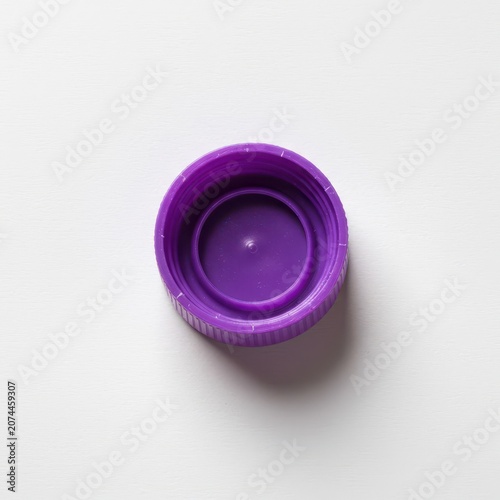 Bright purple plastic bottle cap centered and isolated on a clean seamless white background, showcasing color and texture details, environmental, still life, vivid