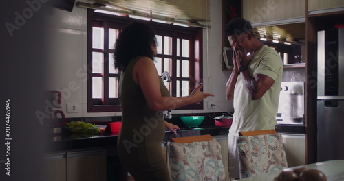 Photos Husband responding with visible frustration as wife argues in kitchen, highlight