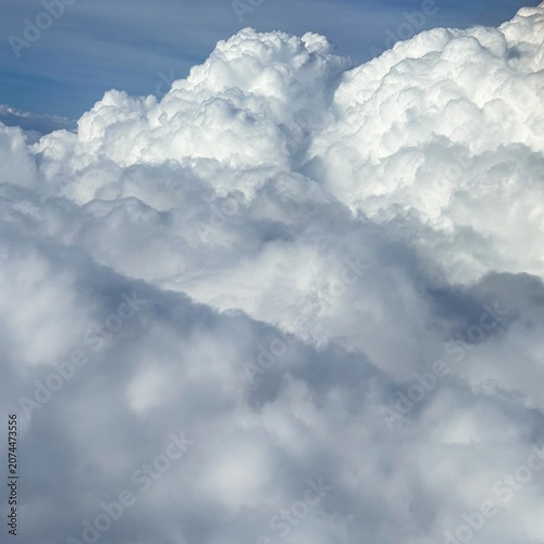 Canvas Print Bright white cumulus clouds fill the sky above a soft haze layer, creating a cal