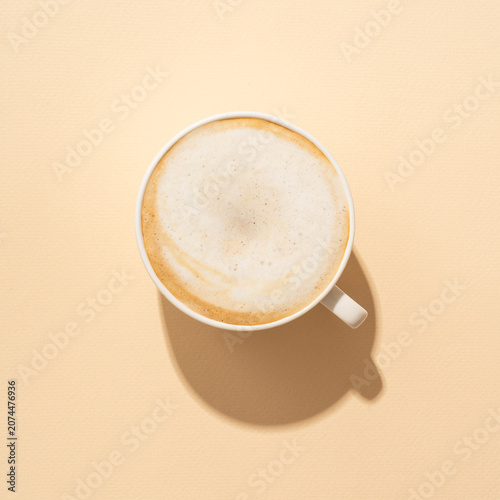 Coffee cup cappuccino foam at colored background with hard shadow.