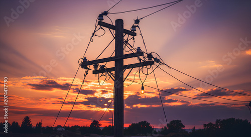 Silhouette of wooden utility pole against a dramatic sunset sky