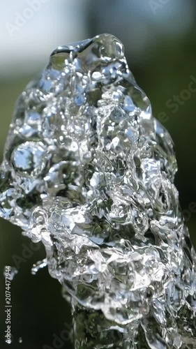 Water jet. Top of water fountain. Flow of pure spring water on a green natural background.