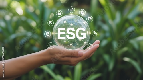 Hand holding transparent sphere with ESG letters and sustainability icons surrounded by green plants symbolizing ethical investment
