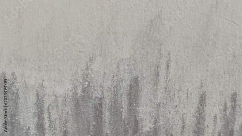 ​The weathered concrete surface exhibits a distinct grunge texture with dark stains and peeling sections
