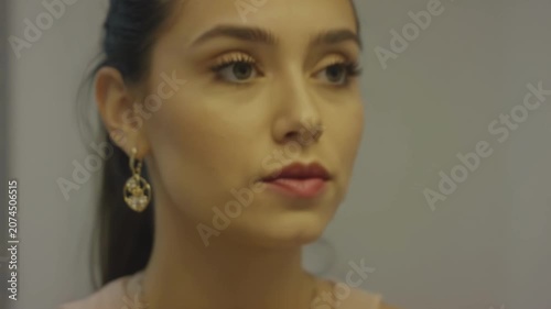 Young woman applying lipstick in front of a mirror, showcasing a close-up of her smile and makeup process in a well-lit indoor setting