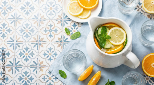 Mediterranean citrus tea setting with fresh lemon slices, herbal infusion, and patterned ceramic tiles, creating a refreshing summer table scene in natural light.