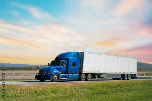 Semi-truck driving on the highway at sunset