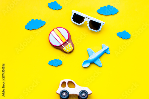 Airplan, car and air balloon toys for family traveling with child on yellow background top view mock-up