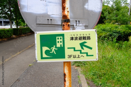 Tsunami evacuation route sign along a green cycling road in Japan.