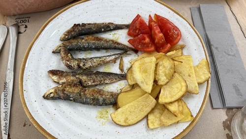 Mediterranean sardines cooking on open fire grill