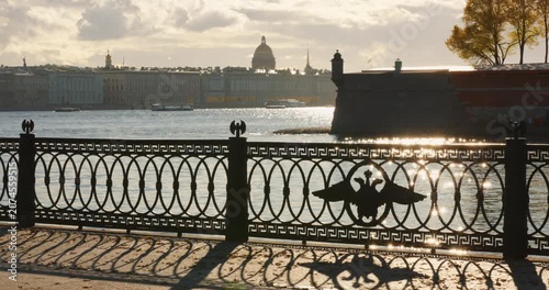 Isaac cathedral, Winter Palace, picturesque metal railings with a double-headed eagle and the crown of the Russian Empire on embankment in St. Petersburg, autumn sunset, incredible sun glare, Russia