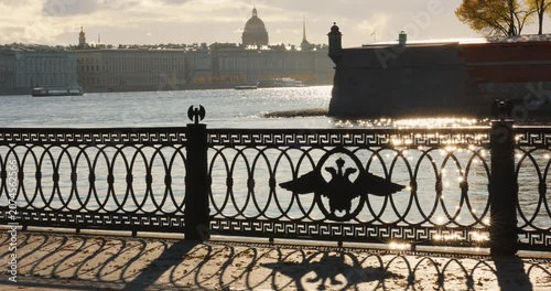 Isaac cathedral, Winter Palace, picturesque metal railings with a double-headed eagle and the crown of the Russian Empire on embankment in St. Petersburg, autumn sunset, incredible sun glare, Russia