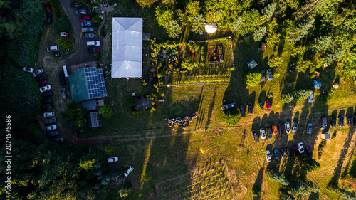 Aerial view of a garden event venue featuring a large white tent, solar panels on a building, and numerous parked cars in a grassy field in Silverton, Oregon, United States.