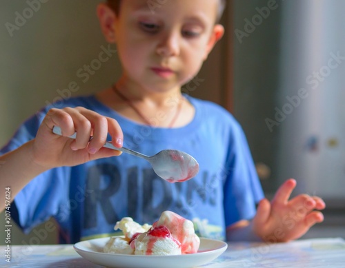 boy lifting a spoonful of sweet yogurt snack from a plate at home