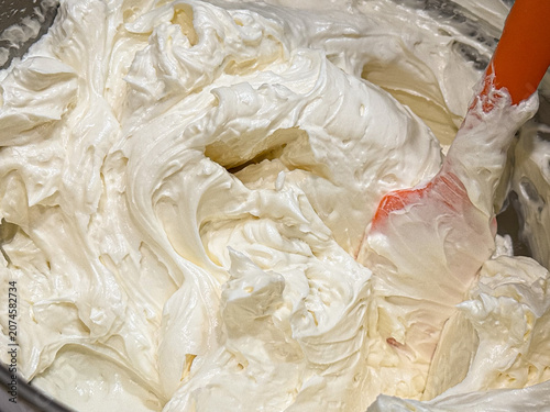 Freshly made Swiss meringue buttercream frosting in mixing bowl with spatula