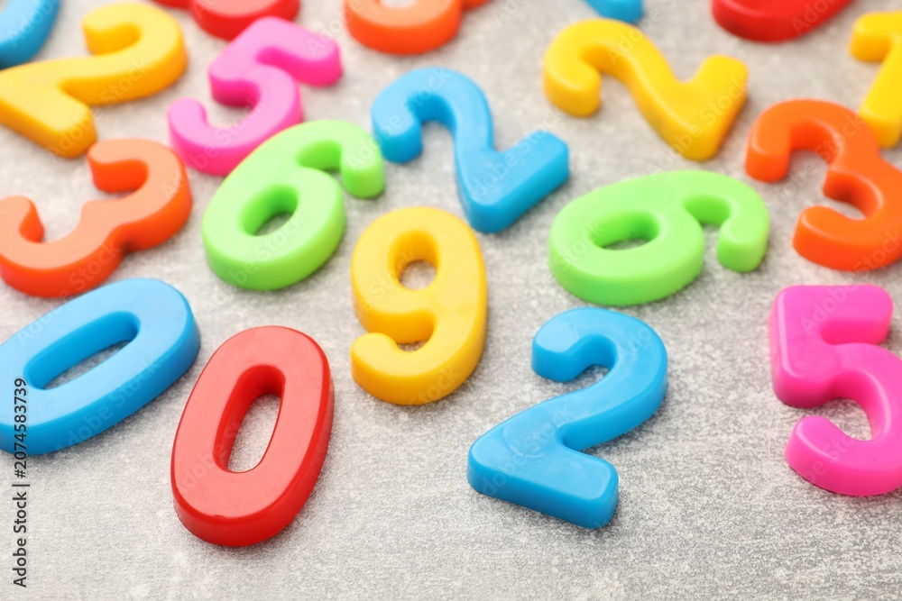 Fototapeta premium Many colorful numbers on grey textured table, closeup