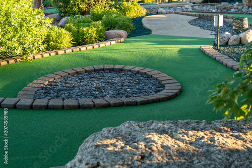 Garden design with green grass and a stone walkway in a mini golf course located in a park, showcasing outdoor landscaping and recreational space horizontal photo