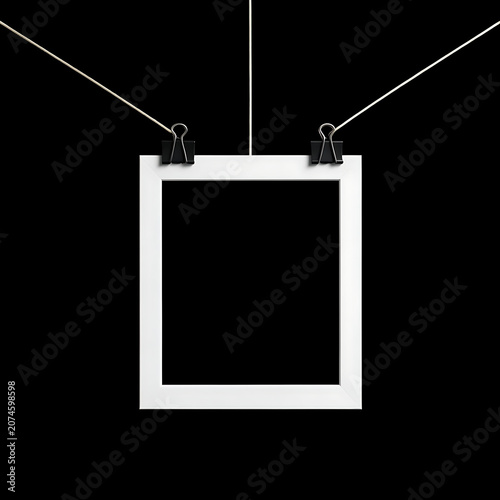 Blank white photo frame hanging with metal binder clips on a solid black background mockup template