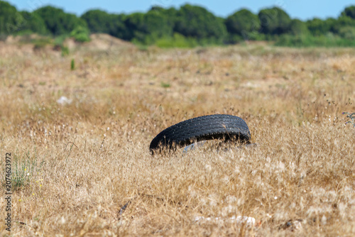 Photos Old discarded car tire abandoned in a dry grassy field.