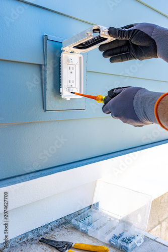 Fotografie Side view of electrician hands using a screwdriver to install a weatherproof out