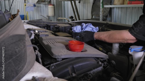 Inspection of the engine and checking the oil level at a service station. After adding oil to the engine, the mechanic checks the oil level.