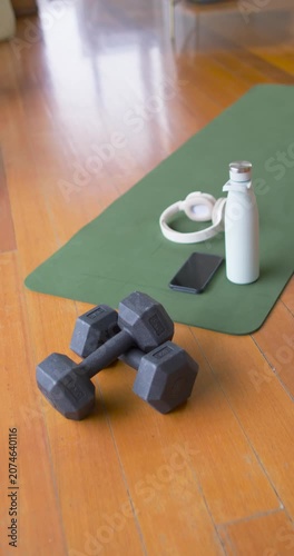 Vertical video: Camera is moving up right, showing mat and bottle while dumbbells staying stacked