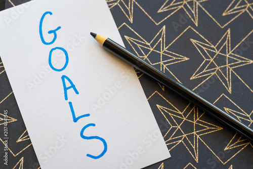 Overhead Angle of Goals Text on a Gold Starry Black Background with a Black Pencil 