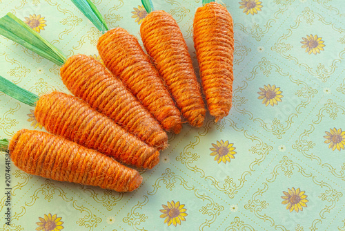 Yarn Woven Orange Carrots on a Green Floral Background