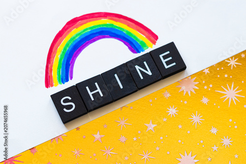 Black and White Shine Text Under a Rainbow on a Golden Starry Background