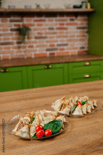 Obraz na płótnie Baked savory pastry triangles on glass plates with cherry tomatoes on a wooden k