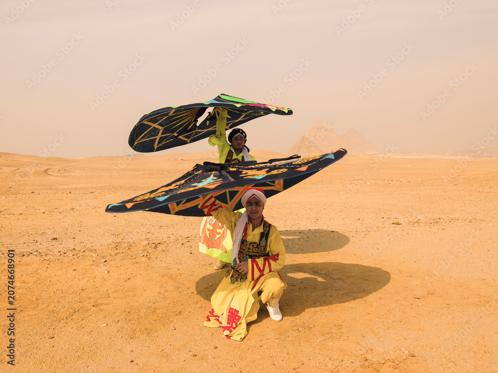 Fototapeta premium Vibrant Tanoura folk dancers spinning colorful skirts overhead in the desert before the Giza pyramids in Egypt ideal for cultural tourism and festival