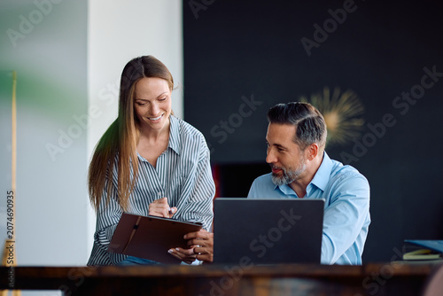 Happy colleagues cooperating while going through busines reports in office.