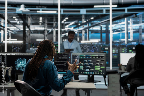 Photography Data center worker monitors system performance and troubleshoots software issues affecting server operations
