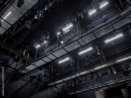 Overhead theater lighting rig with trusses, spotlights and rigging against a dark ceiling, a professional stage technical installation