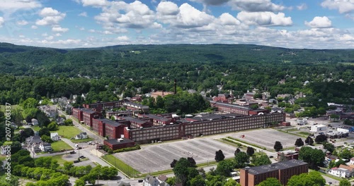 LLION, NY, USA - June 24, 2026: Afternoon summer aerial video of downtown, business district, LLION, NY.  Former Remington Arms factory brick building.