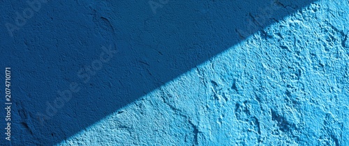 Textured blue wall with a diagonal shadow cutting across it