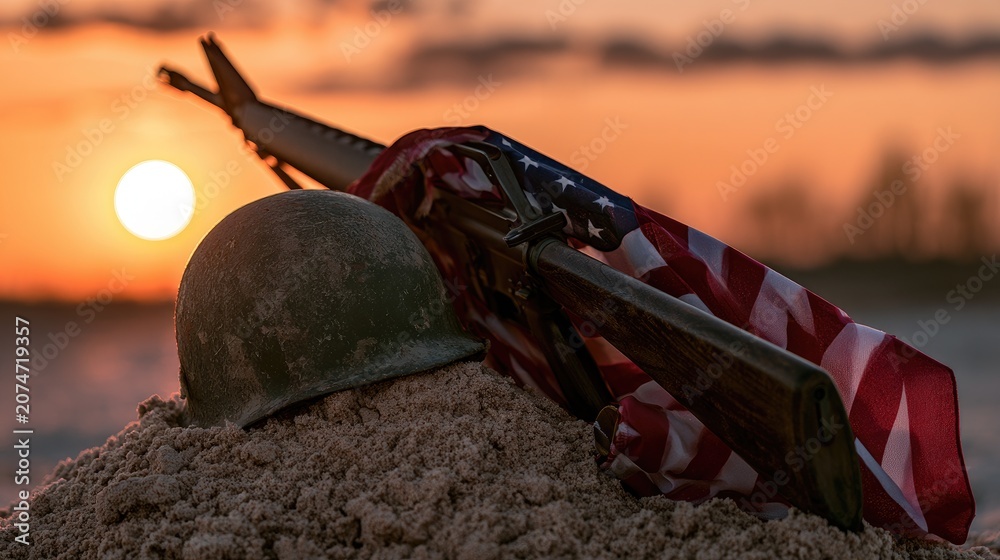 Fototapeta premium A helmet, rifle, and flag rest in sand at sunset