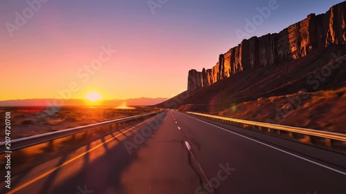 Sunset view over a long desert road and cliffs.